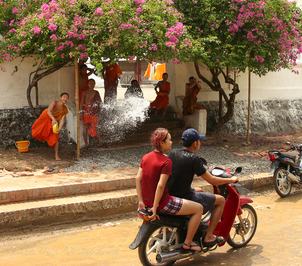 A moment before a monk throws water on a passing scooter